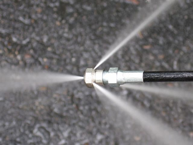 A sewer-jetter hose and nozzle for cleaning a drain.